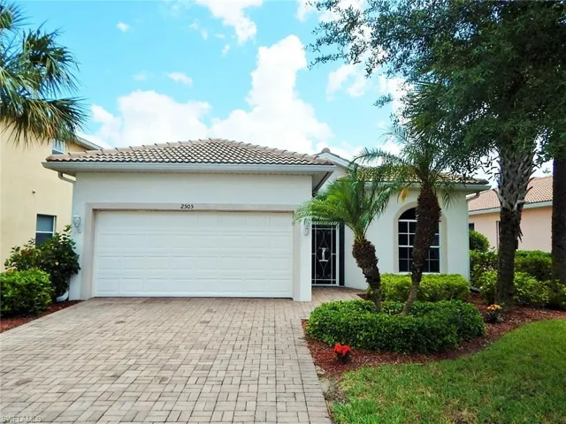 View of front of home featuring stucco siding, decorative driveway, a tiled roof, and a garage