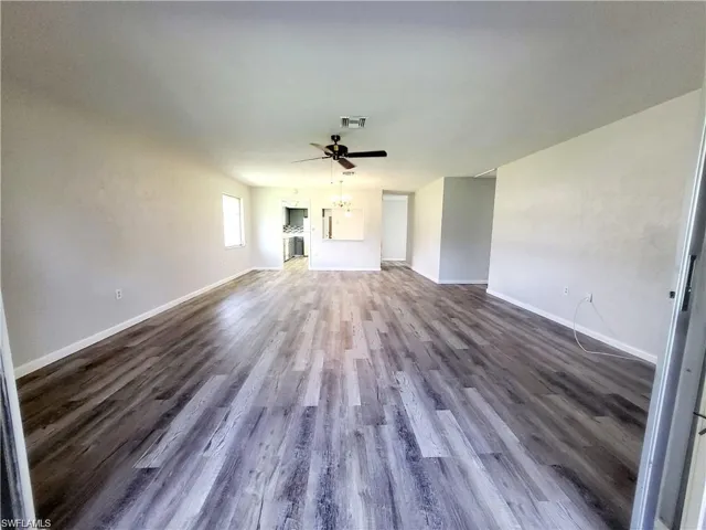 Unfurnished living room with dark wood-style floors and ceiling fan
