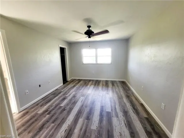 Empty room with dark wood-type flooring and a ceiling fan