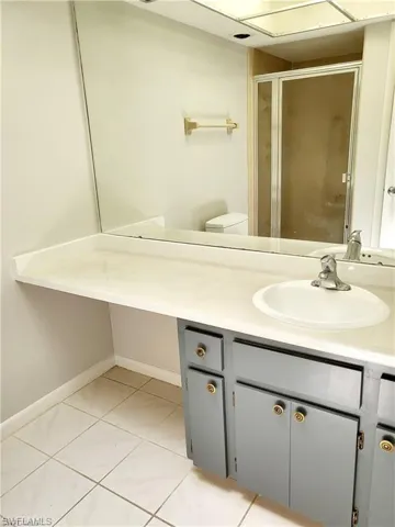 Full bath featuring vanity, light tile patterned flooring, and a stall shower