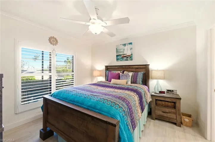 Bedroom with crown molding, ceiling fan, and light wood-style floors