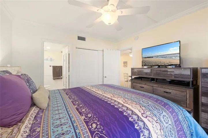 Bedroom with ornamental molding, a closet, ceiling fan, and ensuite bath