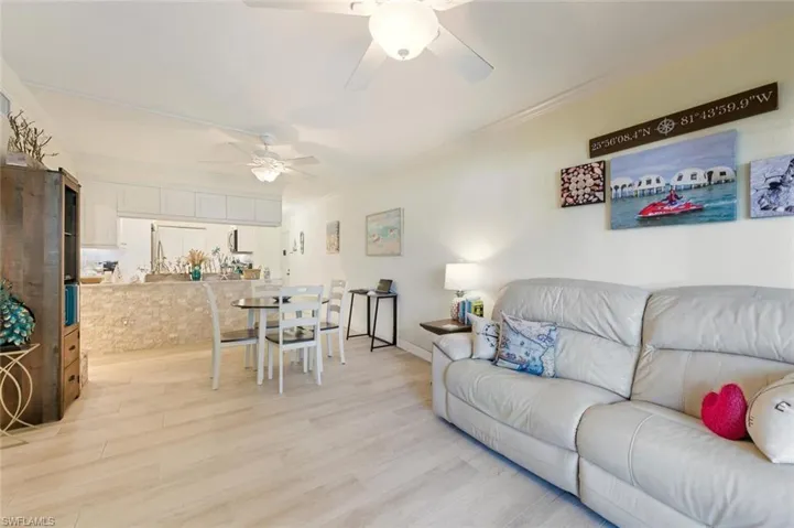 Living room featuring ornamental molding, light wood-style flooring, and ceiling fan