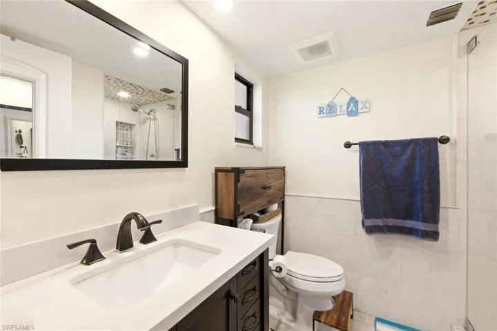 Full bathroom featuring vanity, a tile shower, and tile walls