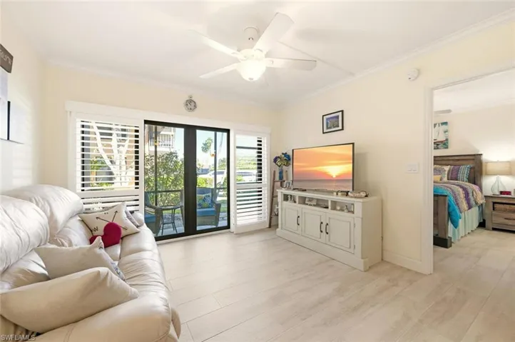 Living room with ornamental molding, ceiling fan, and light wood-style floors