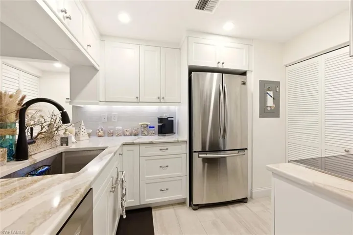 Kitchen featuring stainless steel appliances, white cabinetry, light stone counters, recessed lighting, and backsplash