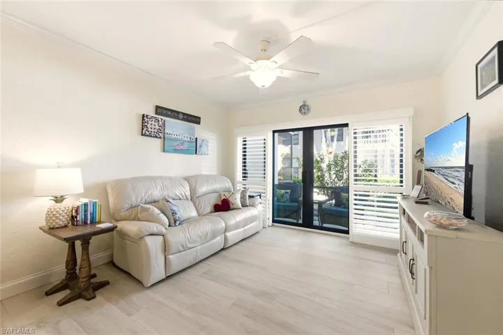 Living area featuring crown molding, light wood finished floors, ceiling fan, and french doors