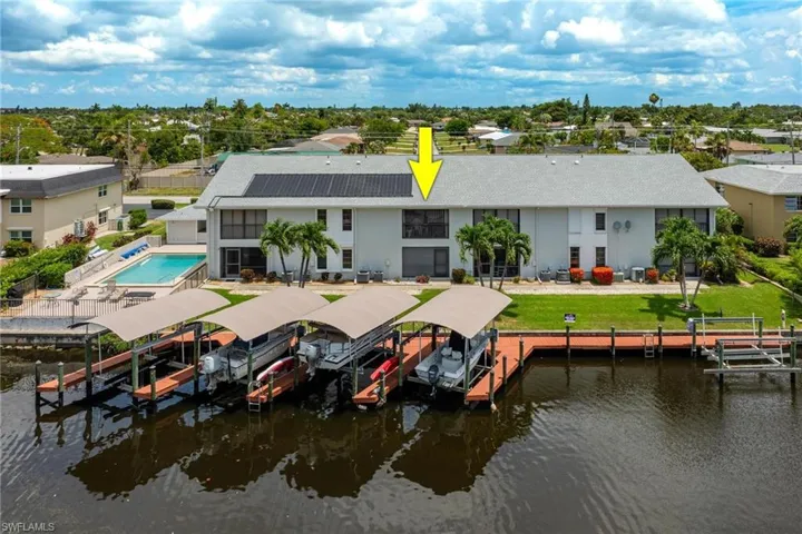 Back of house with boat lift, stucco siding, and a water view