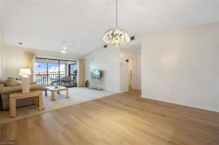 Living area with light wood finished floors, ceiling fan, a chandelier, and vaulted ceiling