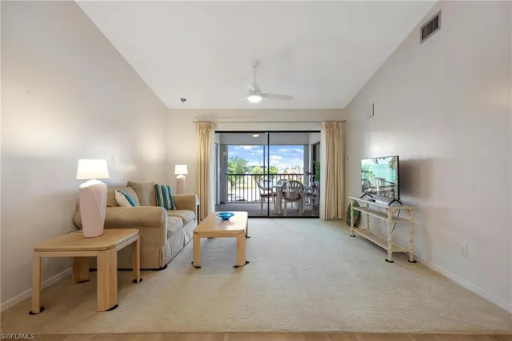 Living area with lofted ceiling, ceiling fan, and light carpet