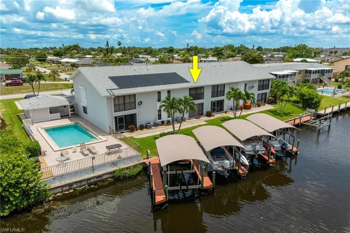 Back of property with boat lift, a patio area, a water view, and a community pool