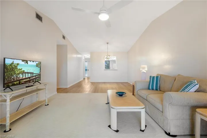 Living area with a ceiling fan, a chandelier, and lofted ceiling