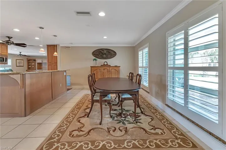Dining room with ornamental molding, light tile patterned floors, and ceiling fan