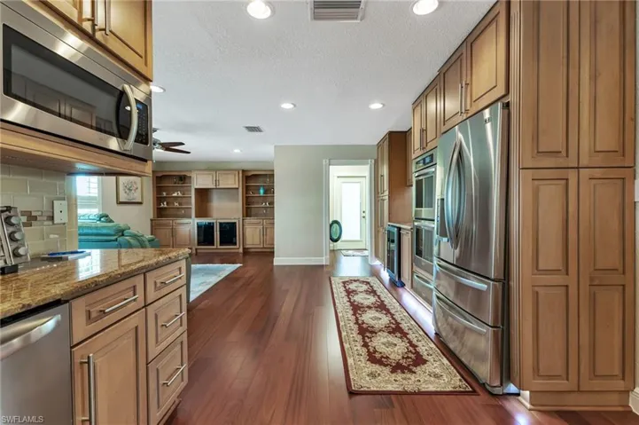Kitchen with ceiling fan, dark wood-type flooring, stainless steel appliances, and backsplash