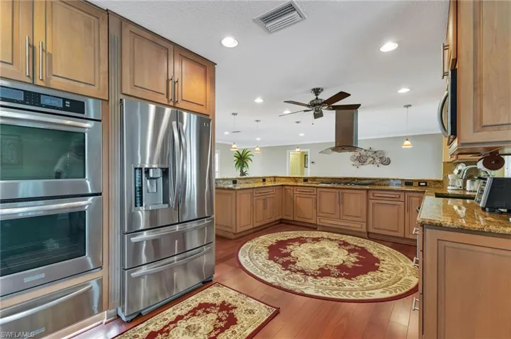 Kitchen featuring appliances with stainless steel finishes, kitchen peninsula, light hardwood / wood-style floors, and exhaust hood
