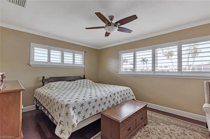 Bedroom with hardwood / wood-style floors, ornamental molding, and ceiling fan
