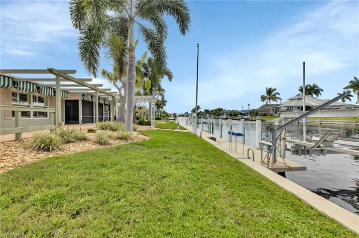Dock area featuring a water view, a pergola, and a lawn