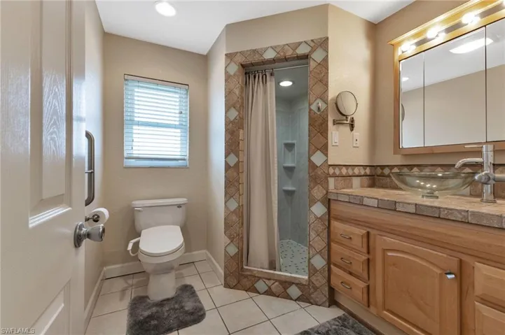 Bathroom with tile patterned floors, vanity, toilet, and a shower with curtain