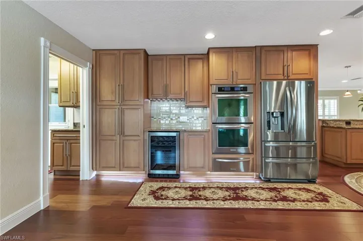 Kitchen featuring wine cooler, stainless steel appliances, dark hardwood / wood-style flooring, and backsplash