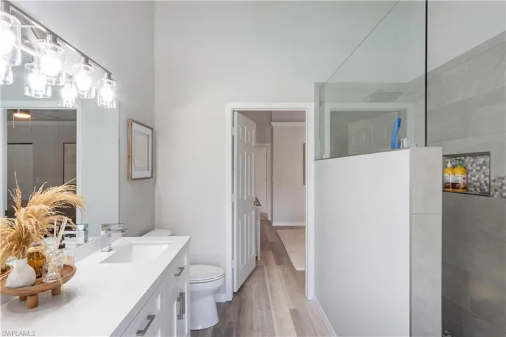 Bathroom featuring a walk in shower, vanity, and light wood-type flooring