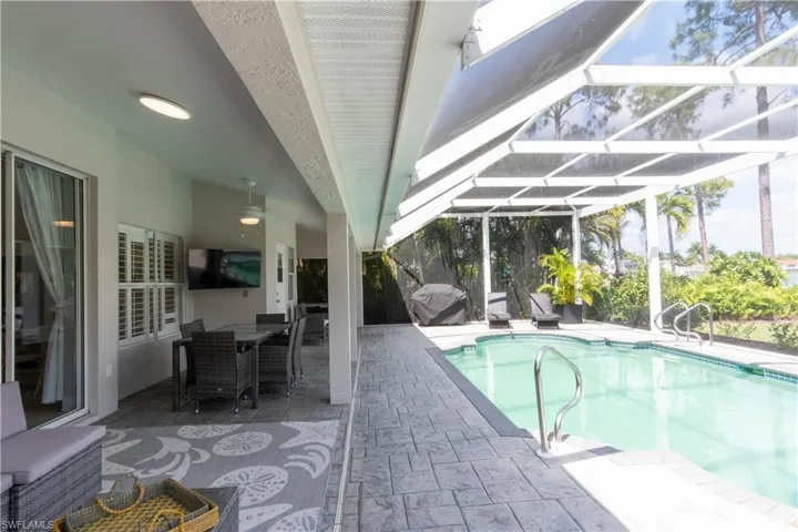 Swimming pool featuring a lanai, a patio, a sunroom, outdoor dining space, and a grill
