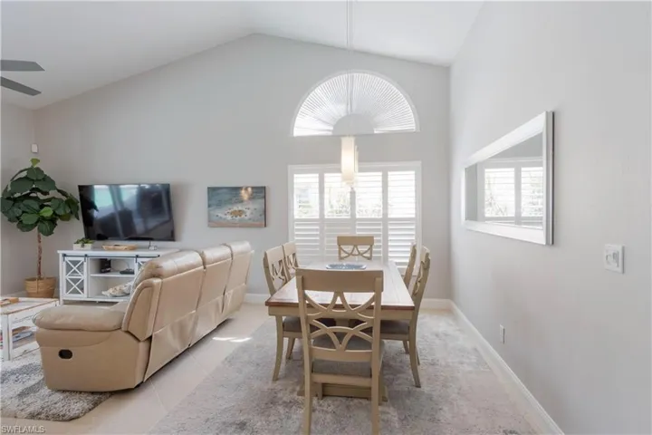 Tiled dining room featuring lofted ceiling and baseboards