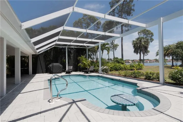 Outdoor pool with a lanai, a patio area, a sunroom, and grilling area