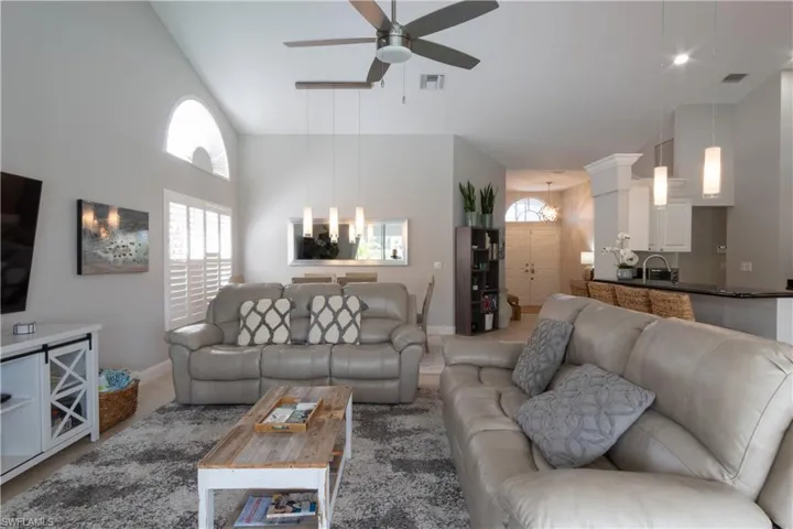 Living room with a ceiling fan, plenty of natural light, and a towering ceiling