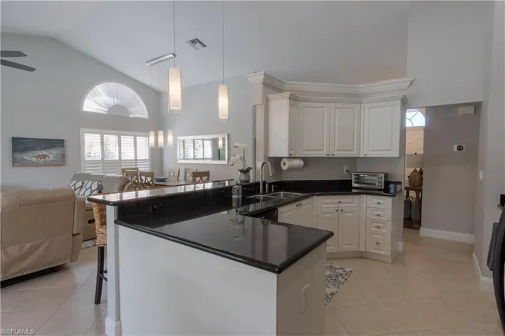 Kitchen featuring open floor plan, a peninsula, pendant lighting, light tile patterned floors, and white cabinets