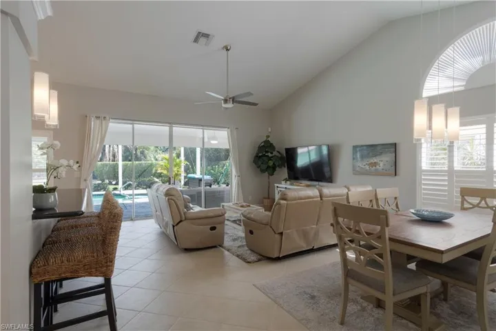 Dining space with high vaulted ceiling, light tile patterned floors, ceiling fan, and healthy amount of natural light