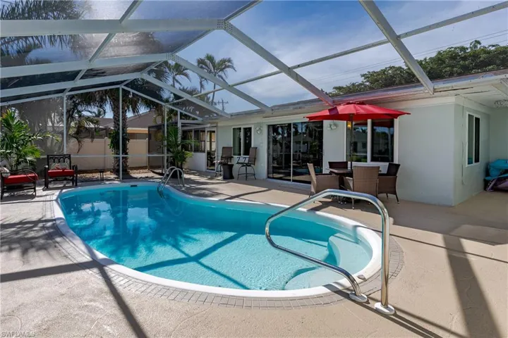 View of swimming pool with glass enclosure and a patio