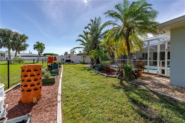 View of yard with a glass enclosure, and lots of gardening space.