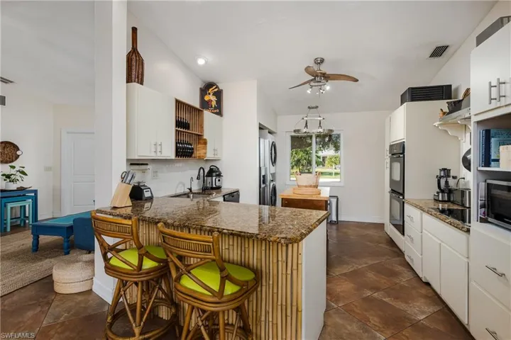 Kitchen with white cabinets, a kitchen breakfast bar, sink, kitchen peninsula, and stainless steel appliances