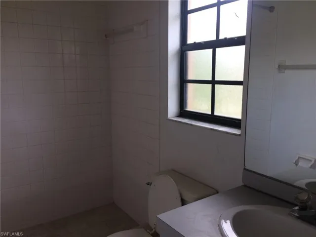 Bathroom with vanity, healthy amount of natural light, and tiled shower