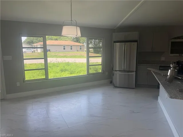This bright interior space features large windows, white tile flooring, and a contemporary light fixture