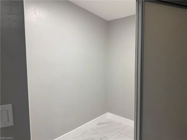 This interior space features light grey walls and white baseboards, complemented by a light-colored tiled floor