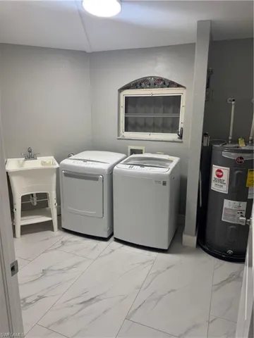 Utility room featuring light grey walls, a sink, and a decorative window