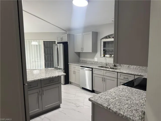The kitchen features extensive granite countertops, light gray cabinetry, and stainless steel appliances