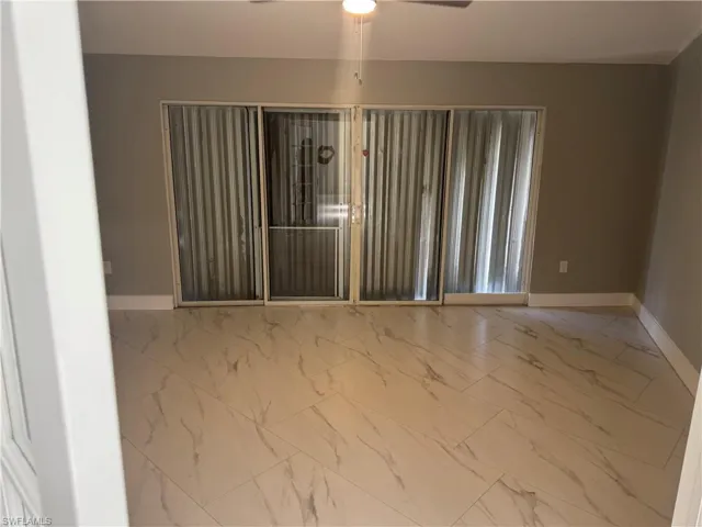 This spacious room features neutral-toned walls, contemporary tile flooring, and large sliding glass doors