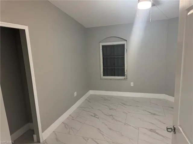 This room features modern tile flooring, light gray walls, a window with an arched top, and a ceiling-mounted light fixture