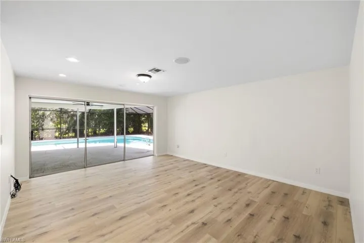 Unfurnished room with wood finished floors, a sunroom, and recessed lighting