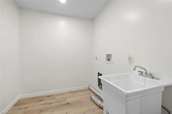 Laundry area with hookup for a washing machine and light wood-type flooring