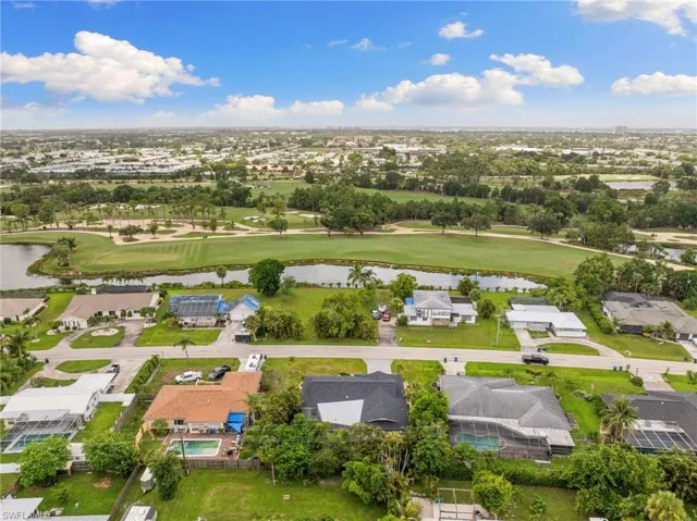 Aerial view of residential area featuring a local golf course and a nearby body of water