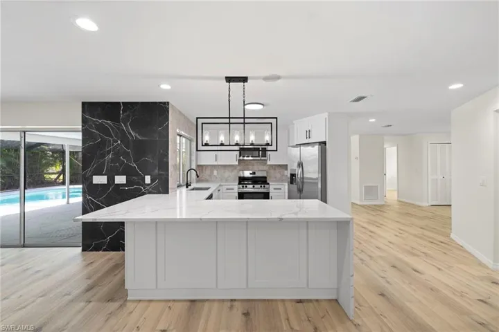 Kitchen featuring stainless steel appliances, light stone countertops, recessed lighting, a peninsula, and white cabinets