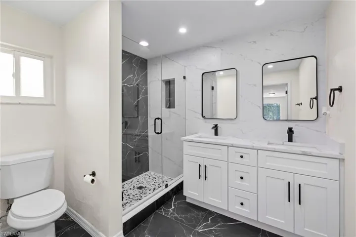 Full bathroom with marble finish floors, a marble finish shower, recessed lighting, and double vanity