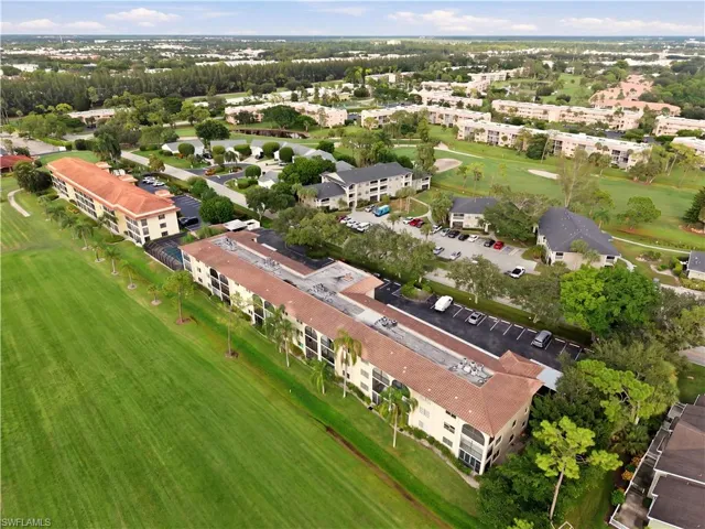 Residential community with multiple buildings, lush green landscaping, and a golf course