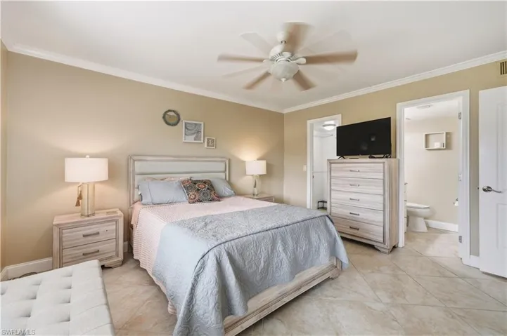 Crown molding detail, ceiling fan fixture, tile flooring, interior door, and a built-in closet