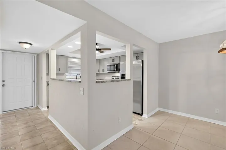 Kitchen with stainless steel appliances, light tile patterned floors, a ceiling fan, and light stone countertops