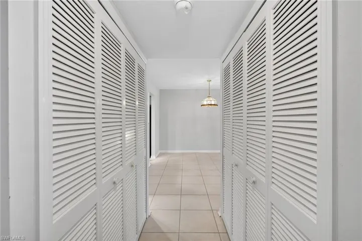 Hallway with light tile patterned flooring and baseboards