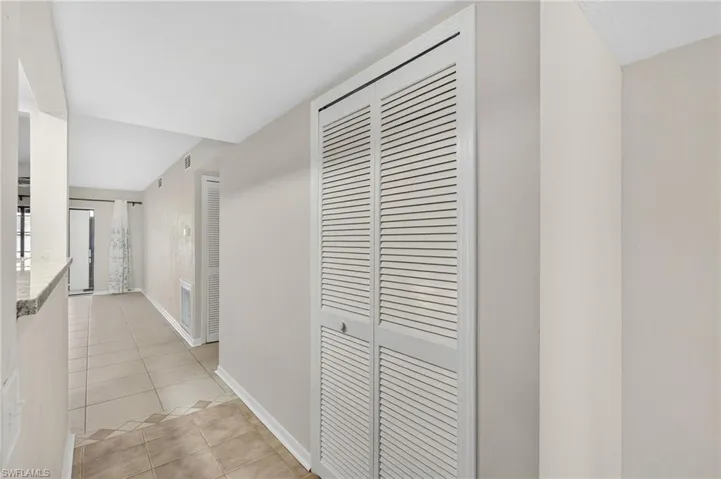 Hallway featuring light tile patterned flooring and baseboards